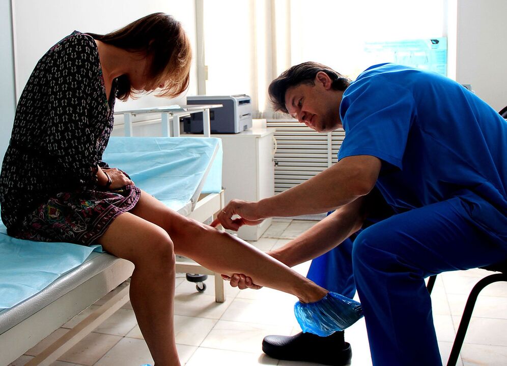 doctor examines the leg with varicose veins